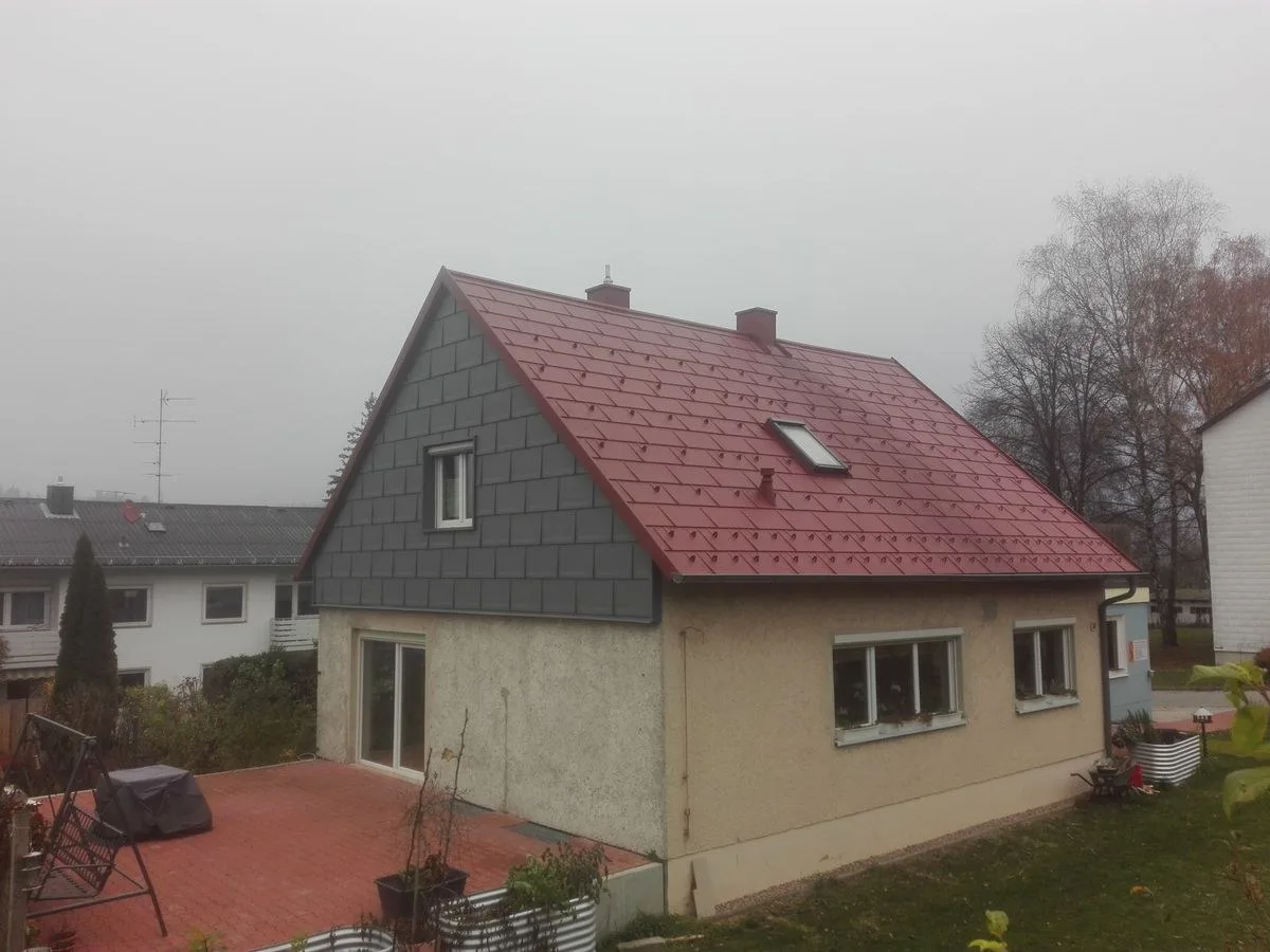 Wohnhaus mit rotem Dach und grau verkleidetem Giebel
