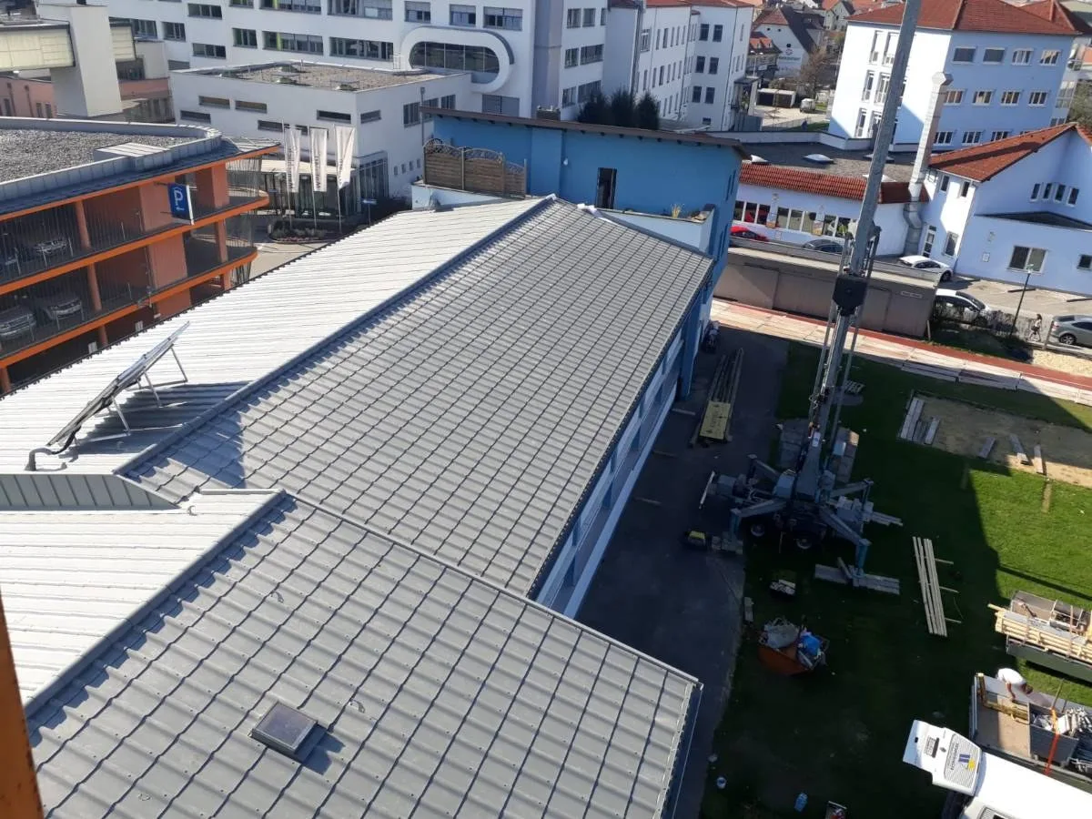 Graues Dach der Jahnturnhalle während der Arbeiten, daneben ein Kran
