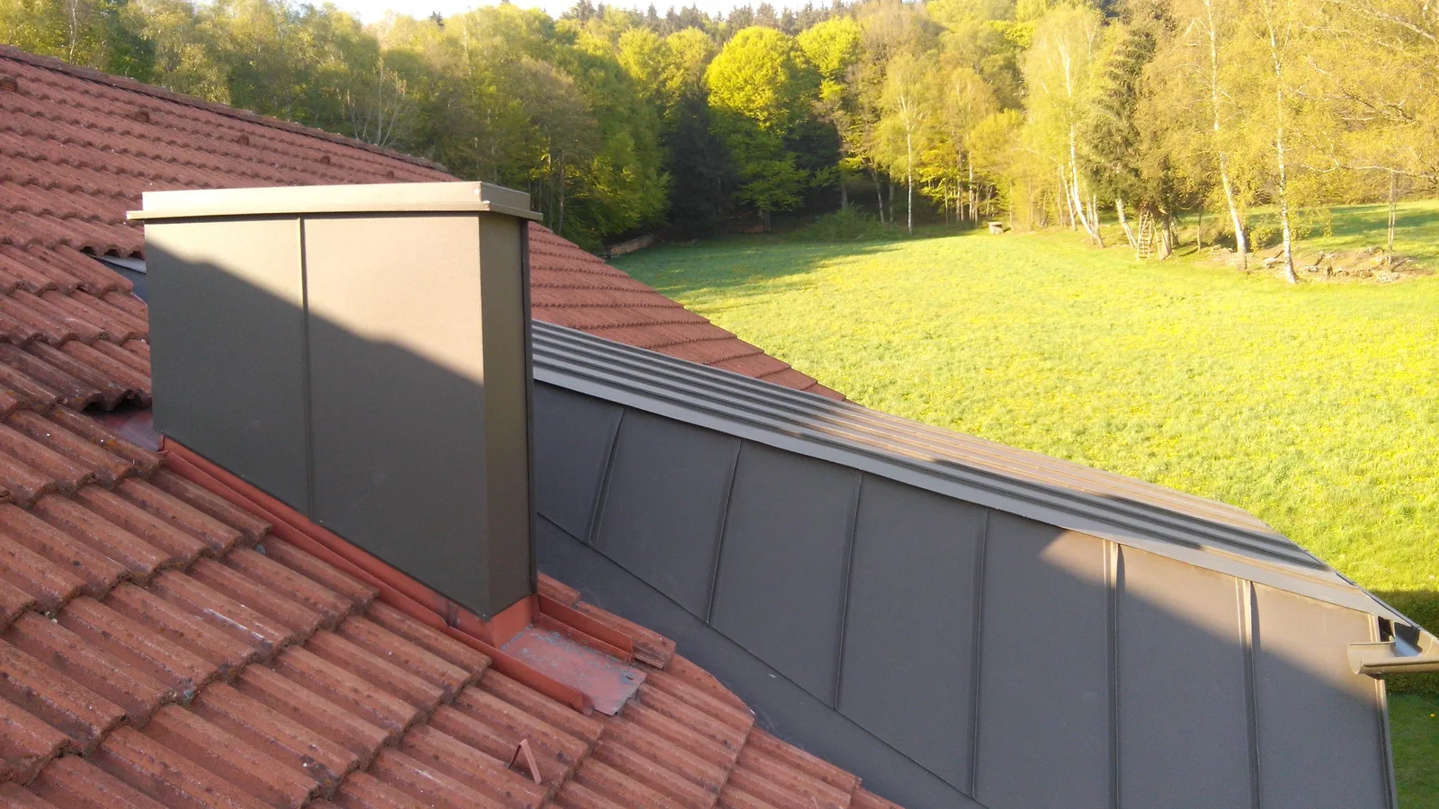 Verblechter Kamin und Blechfläche neben einem Ziegeldach